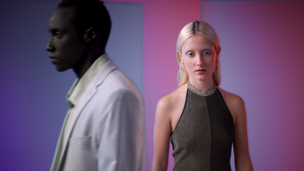 Peachy Keen Colourist Angela Cerasi colour graded this medium close up shot of a white, blond model in a gold dress and a black male model in a white suite, in a blue & red lit room, for the Afterpay Australian Fashion Week TVC campaign for LG X Harvey Norman