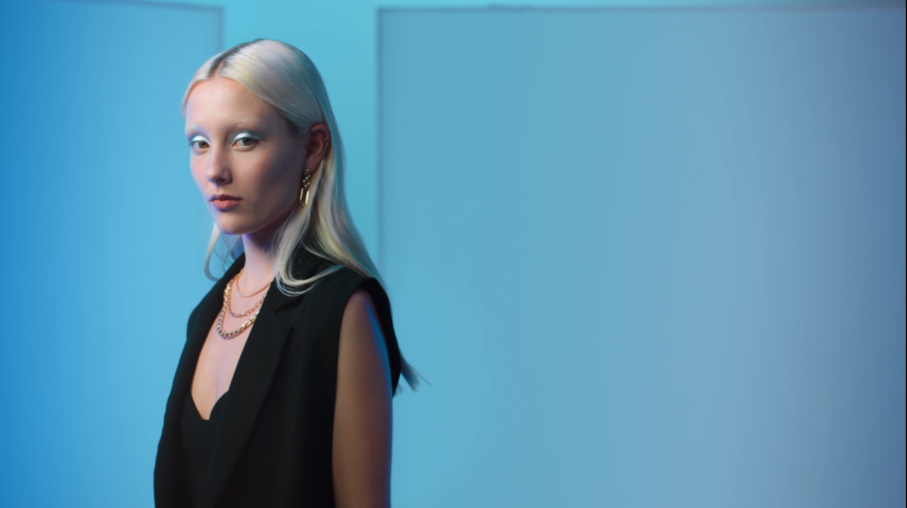 Peachy Keen Colourist Angela Cerasi colour graded this mid shot of a white, blond model with blue eyeshadow and a black dress, standing in a blue-lit room, for the Afterpay Australian Fashion Week TVC campaign for LG X Harvey Norman in this example of colour grading video