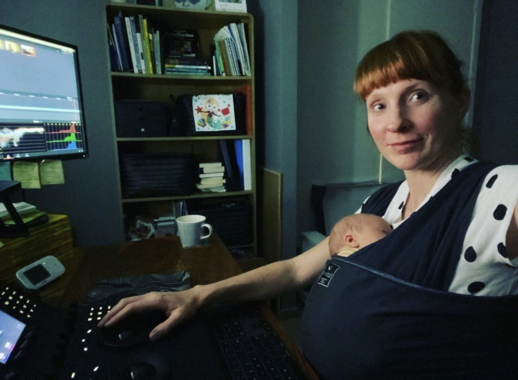 Peachy loves Mums in Ads because we've been there. Senior Colourist Angela Cerasi created a flexible work life balance when founding Peachy Keen Colour. Here she is pictured fitting in a colour grade while her baby sleeps on her in a dark blue carrier.