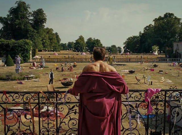 The visual language of Saltburn - image from the film of a man in a red dressing gown looking over a balcony